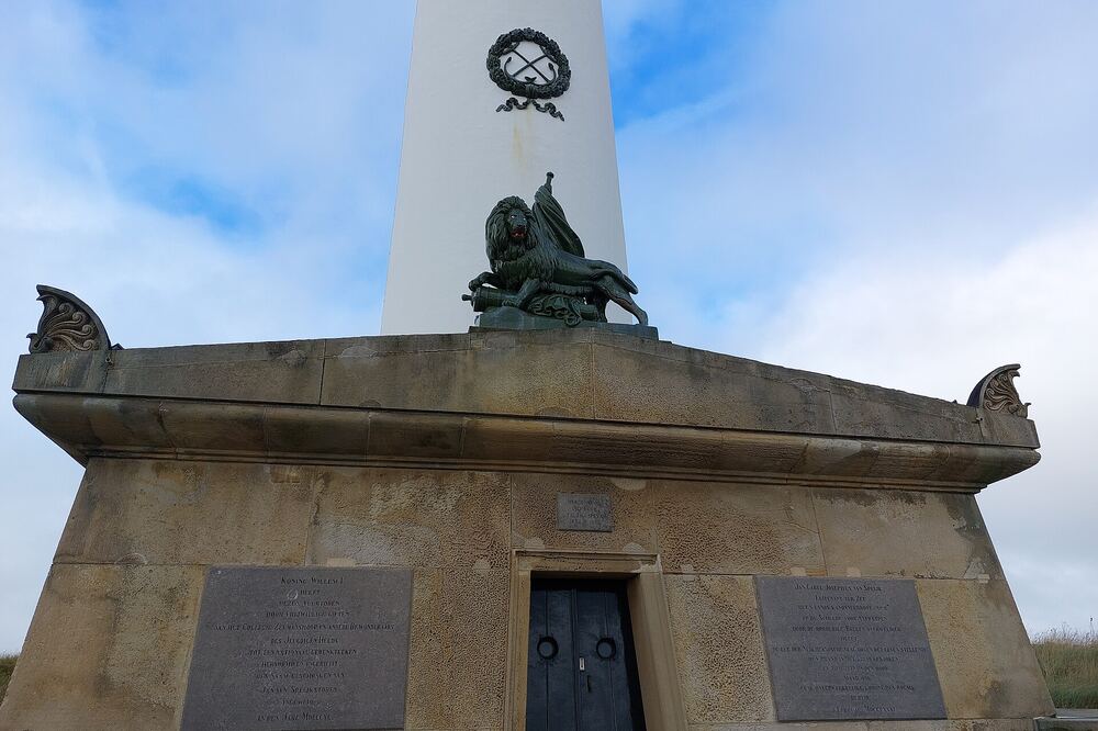 Stenen grafmonument van Van Speijk met gedenkplaten, direct aan de voet van de witte vuurtoren van Egmond aan Zee
